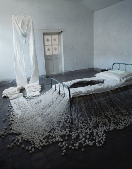 “The Proliferation of Thread Winding,” 1995. White cotton thread, rice paper, 20,000 needles (12-15 cm in length), bed, video player, television monitor. Dimensions variable. Open Studio, Baofang Hutong 12#, Beijing, 1995. Collection of the artist. Courtesy Galerie Lelong.