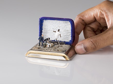 TALWST, Por qué?, 2015. reclaimed 1950’s ring box, model putty, plastic, crushed rock, gold leaf, Acrylic paint, 3vled light.3v coin battery. Flag: encaustic and ball point pen on gauze/7.5x7.5 cm. Image courtesy of the Artist. Photo: Todd Duym.