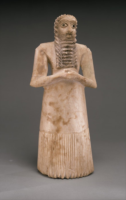 <em>Standing Male Worshiper</em>, Sumerian, ca. 2900-2600 B.C. Gypsum alabaster, shell, black limestone, bitumen, 11 5/8 x 51/8 x 3 7/8 in. Courtesy of the Metropolitan Museum of Art.
