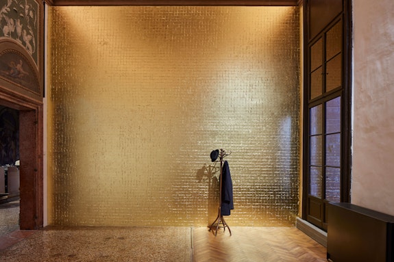 Jannis Kounellis, Untitled (Tragedia civile), 1975. Goldleaf-coated wall, coat rack, coat, hat, lamp. Courtesy Fondazione Prada. Photo: Agostino Osio - Alto Piano.