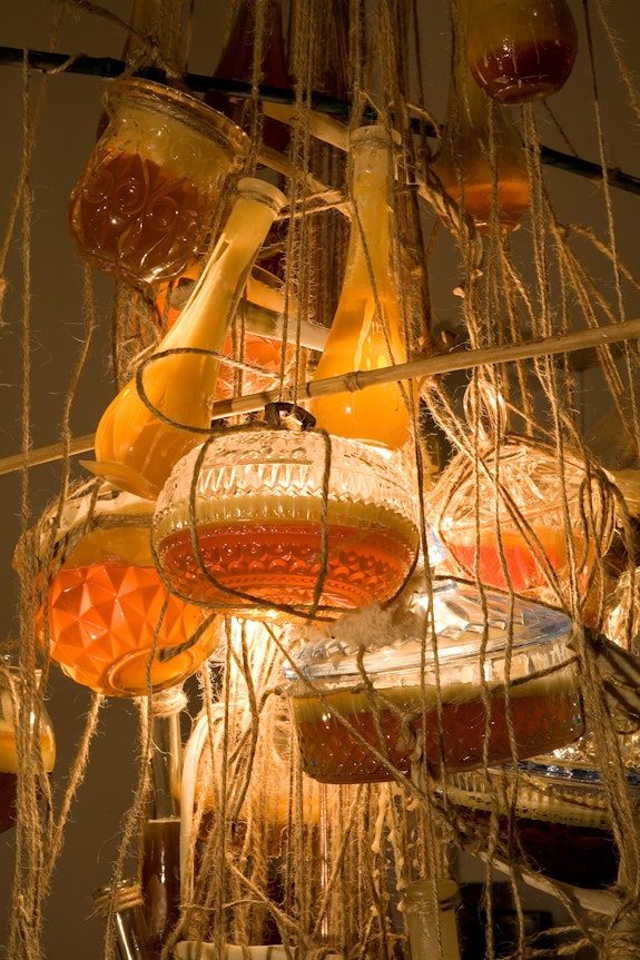 Lauren Bon, <em>Honey Chandelier,</em> 2007. Honey acquired from war-torn countries around the world (2001–7). Collected jars, wire, burlap, hessian, light bulbs. 60 × 48 × 40 in. Courtesy the artist.<strong> </strong>Photo: Joshua White.