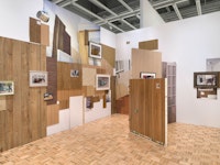 Installation view: <em>Rachel Harrison Life Hack</em>, Whitney Museum of American Art, New York, 2019--2020. <em>Should home windows or shutters be required to withstand a direct hit from an eight-foot-long two-by-four shot from a cannon at 34 miles an hour, without creating a hole big enough to let through a three-inch sphere?</em>, 1996/2019. Photo: Ron Amstutz.