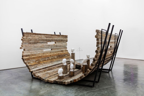 Radcliffe Bailey, <em>Nommo</em>, 2019. Mixed media and sound installation including a radio, found wood, steel metal structure and 8 plaster busts, approx. 120 x 252 x 156 inches. © Radcliffe Bailey. Courtesy Jack Shainman Gallery, New York.