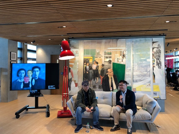 Zhang Xiaogang (wearing a baseball cap) giving a talk to museum patrons in the M+ Lounge. Courtesy the author.