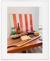 Valentim's Airbnb buffet at his home, with Buren's original stripes from his 1980 show, purchased directly from the gallerist by Valentim, alongside a collector's edition box of the iconic French cheese, <em>La vache qui rit</em>, Buren designed in 2019. Courtesy the artist.