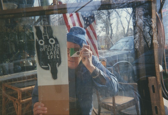 Ray Johnson, <em>RJ with PLEASE SEND TO REAL LIFE and camera in mirror</em>, 1994. Commercially processed chromogenic print, 4 x 6 inches. Courtesy the Ray Johnson Estate.  