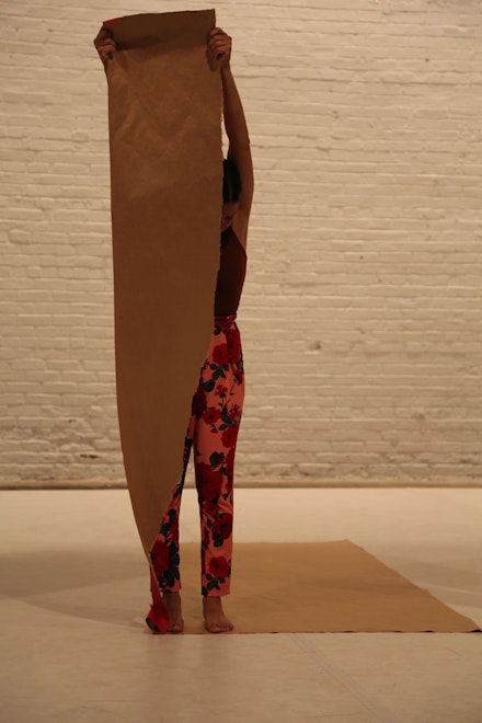 Abril holds a long strip of brown paper vertically, at arms’ length. Photo: Brian Rogers.