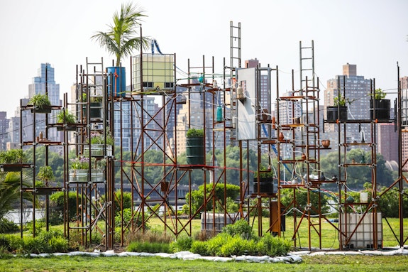 Mary Mattingly, <em>Water Clock, Ebb of a Spring Tide at Socrates Sculpture Park, Queens, NY</em>, 2023. Reused steel, bins, doors, ladders, a bed frame, and East River water, 16 x 65 x 26 feet. The water clock tells time by responding to the East River's tides and grows salt-tolerant halophyte plants. Photo: Scott Lynch.